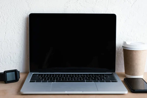 Ноутбук з порожнім екраном, смарт-годинник, смартфон і кава, щоб піти на стіл — стокове фото