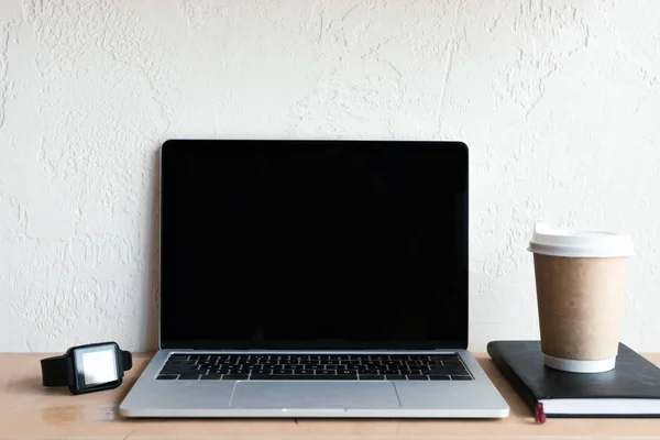 Ordinateur portable avec écran blanc, smartwatch, ordinateur portable et café pour aller sur la table — Photo de stock