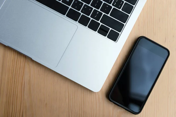 Vue de dessus de l'ordinateur portable et smartphone avec écran noir sur table en bois — Photo de stock