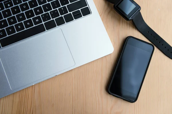 Vue de dessus de l'ordinateur portable, smartwatch et smartphone avec écran blanc sur la table en bois — Photo de stock