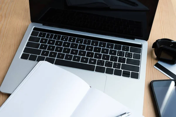 Laptop, smartwatch, smartphone, credit card and blank notebook on table — Stock Photo