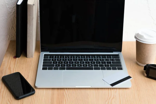 High angle view of laptop with blank screen, credit card and smartphone on wooden table — Stock Photo