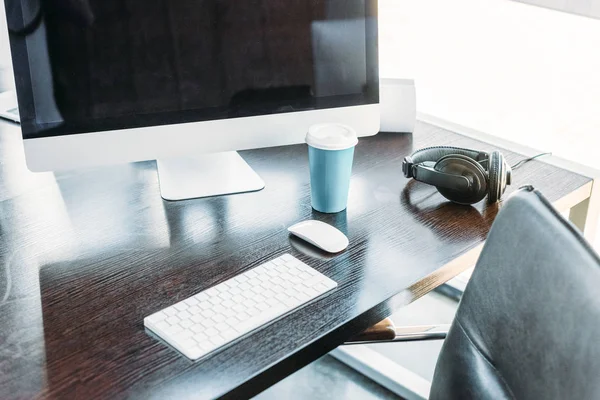 Table with computer, keyboard and cup of coffee in office — Stock Photo