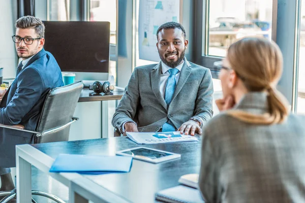 Empresários multiculturais falando à mesa no escritório — Fotografia de Stock