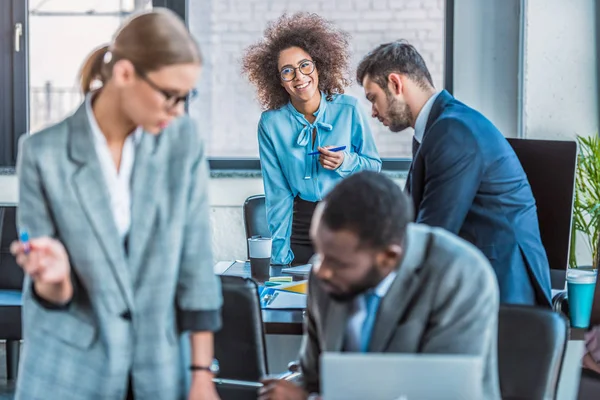 Lächelnde afrikanisch-amerikanische Geschäftsfrau blickt im Büro in die Kamera — Stockfoto