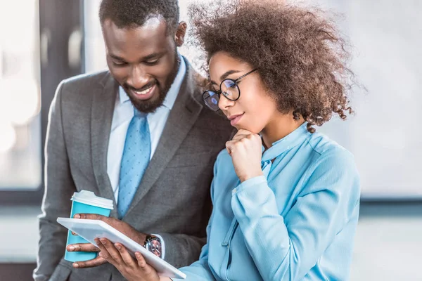 Souriants hommes d'affaires afro-américains regardant tablette dans le bureau — Photo de stock