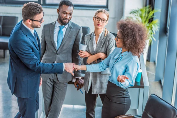 Multicultural businesspeople shaking hands in office — Stock Photo