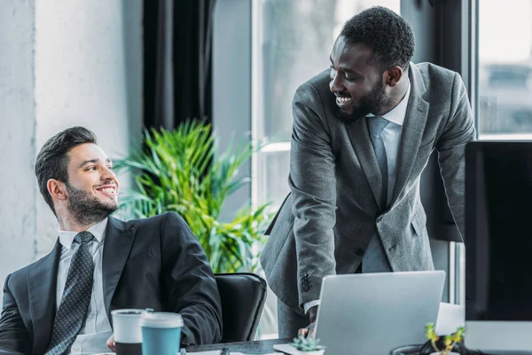 Smiling multicultural businessmen talking at looking at each other — Stock Photo