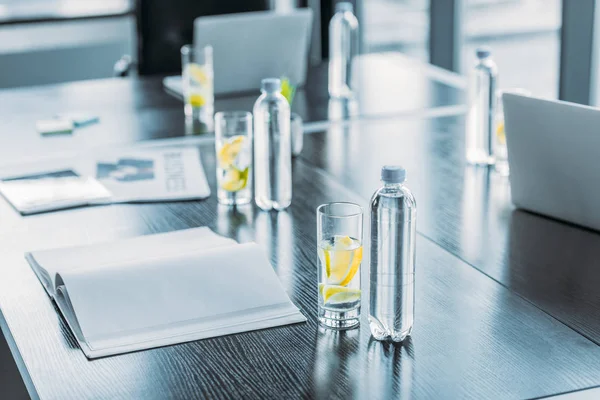 Botellas y vasos con bebida antioxidante para reuniones de negocios en la mesa en el espacio de trabajo - foto de stock