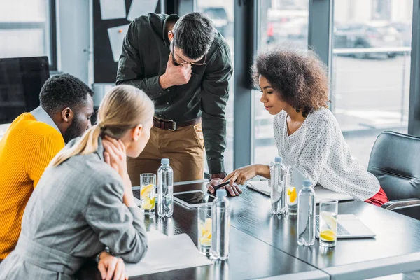 Multikulti-Geschäftsleute schauen im Büro auf Tablet — Stockfoto