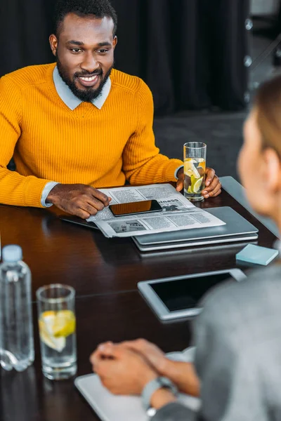 Multicultural businessman and businesswoman sitting in office with detox drink — Stock Photo