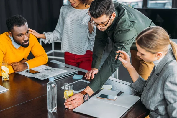 Hombre de negocios tomando un vaso de bebida desintoxicante de la mesa en la oficina - foto de stock