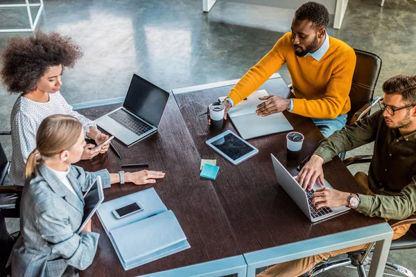 Vista ad alto angolo di imprenditori multiculturali che lavorano con dispositivi digitali in ufficio — Foto stock