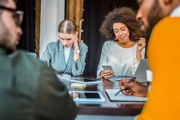 Des gens d'affaires multiculturels avec des gadgets sur la table au bureau — Photo de stock