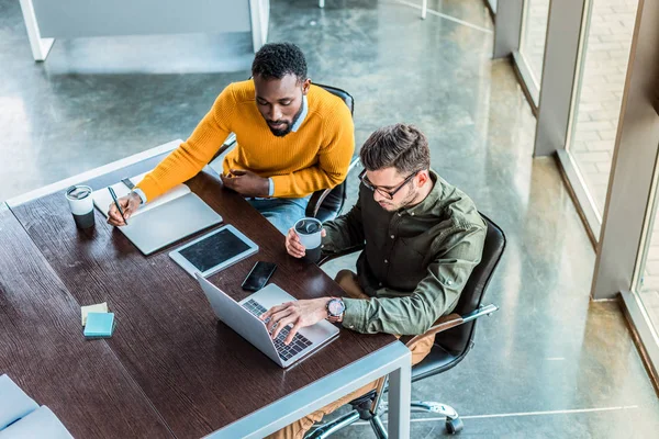 Vue grand angle des hommes d'affaires multiculturels regardant ordinateur portable dans l'espace de travail — Photo de stock