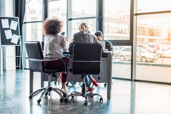 Vista posteriore di imprenditori multiculturali seduti a tavola nello spazio di lavoro — Foto stock
