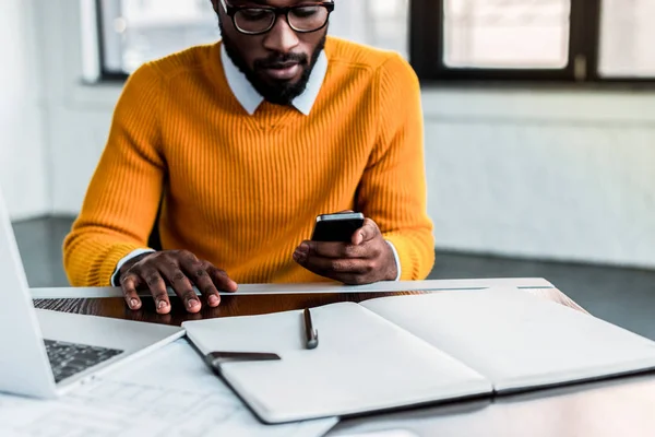 Hombre de negocios afroamericano usando smartphone en la oficina - foto de stock