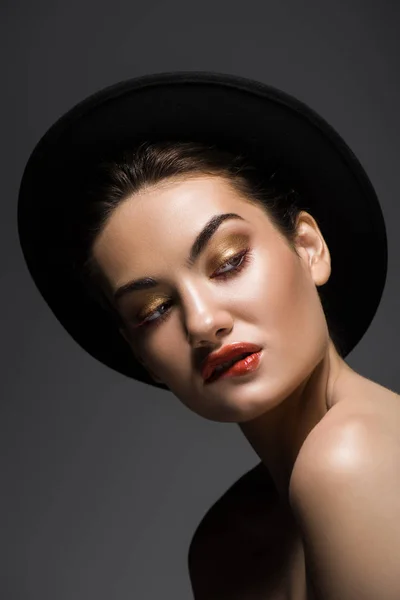 Beautiful seductive girl in black felt hat biting lip, isolated on grey — Stock Photo