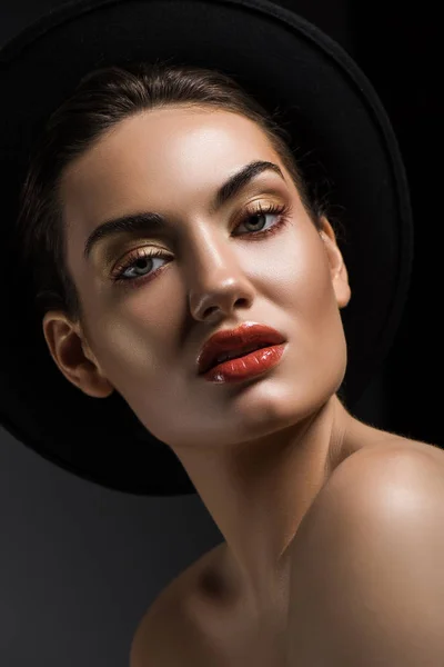 Elegantes Mädchen mit Make-up posiert in schwarzem Filzhut, isoliert auf grau — Stockfoto