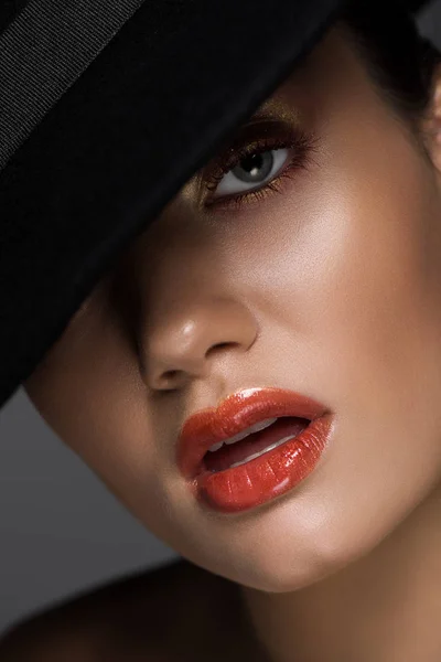 Hermosa mujer sensual con maquillaje posando en sombrero de fieltro negro, aislado en gris - foto de stock