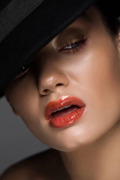 Sensual model with makeup posing in black felt hat, isolated on grey — Stock Photo