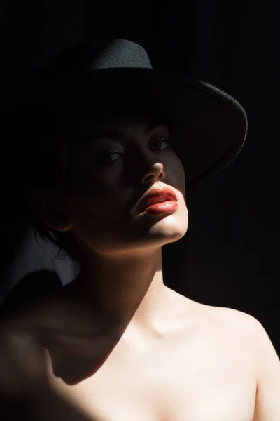 Belle fille élégante en feutre noir chapeau posant dans l'obscurité — Photo de stock