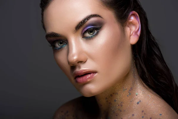 Fashionable young woman posing with glitter makeup, isolated on grey — Stock Photo