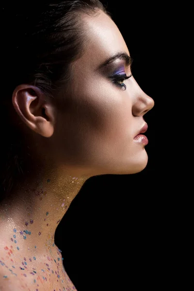 Profile portrait of attractive glamorous woman posing with makeup and glitter on body, isolated on black — Stock Photo