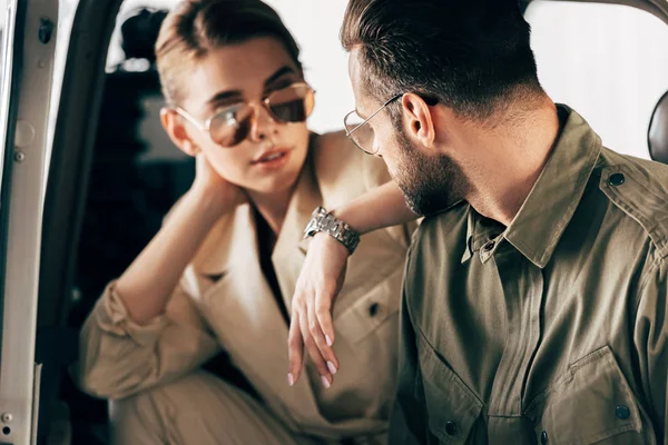 Close up view of stylish couple in jackets looking at each other near airplane — Stock Photo