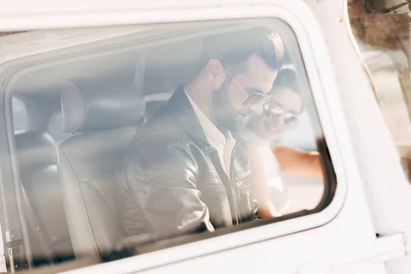 Side view of male pilot in sunglasses and leather jacket with girlfriend sitting near in cabin of airplane — Stock Photo