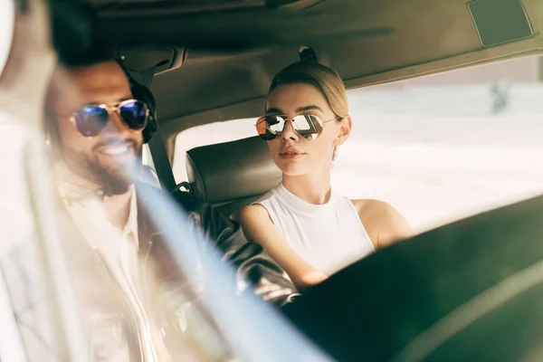 Piloto masculino sonriente en auriculares y gafas de sol sentado con novia en cabina de avión - foto de stock