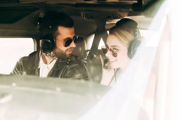 Мужчина-пилот в наушниках и солнцезащитных очках разговаривает с девушкой в салоне самолета — стоковое фото