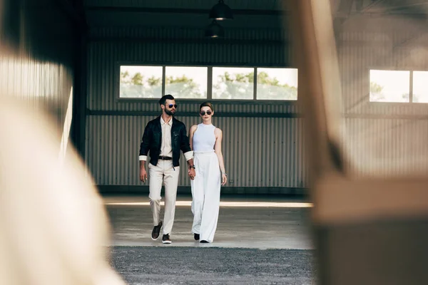 Foyer sélectif de l'homme élégant en veste en cuir et lunettes de soleil tenant la main avec petite amie — Photo de stock