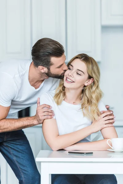 Handsome young man kissing smiling girlfriend at morning — Stock Photo