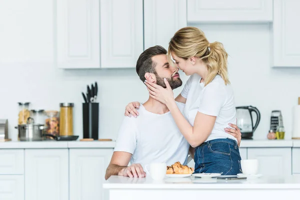 Bella felice giovane coppia innamorata baciare durante la colazione in cucina — Foto stock