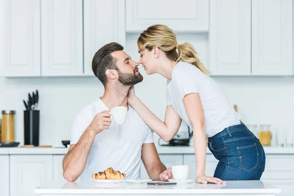 Beautiful young couple in love able to kiss while having breakfast together — Stock Photo