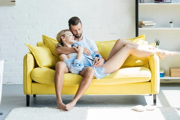 Beau tendre jeune couple amoureux étreignant sur canapé jaune à la maison — Photo de stock