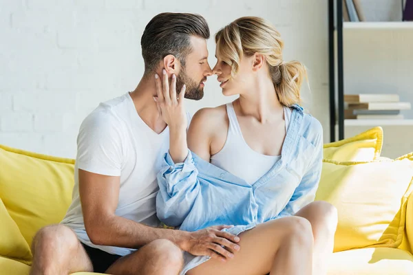 Heureux passionné jeune couple en mesure d'embrasser sur canapé à la maison — Photo de stock