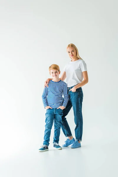 Mère en vêtements décontractés étreignant son fils et ils regardent la caméra sur blanc — Photo de stock