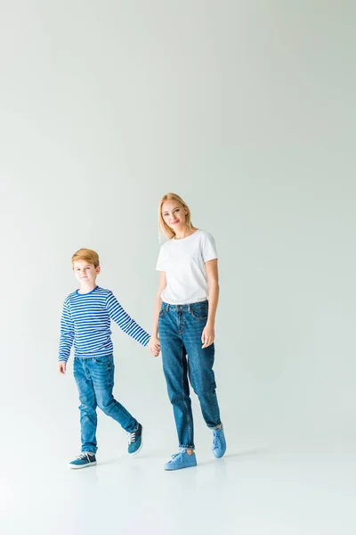 Madre e hijo tomados de la mano en blanco y mirando a la cámara - foto de stock