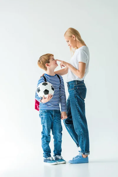 Мать трогает сына нос, он держит футбольный мяч на белом — стоковое фото