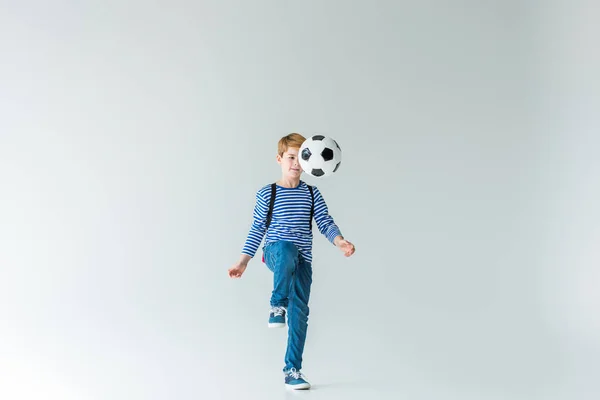 Adorable schoolboy with backpack playing fotball on white — Stock Photo
