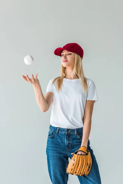 Attractive baseball player in red cap throwing up baseball ball isolated on white — Stock Photo