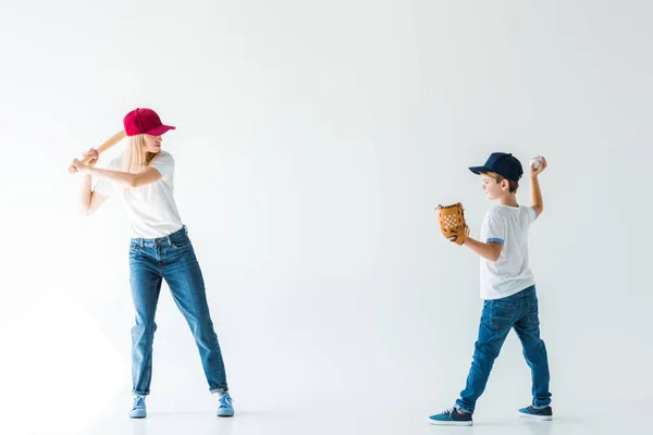 Seitenansicht von Sohn wirft Baseballball auf Mutter mit Baseballschläger isoliert auf weiß — Stockfoto