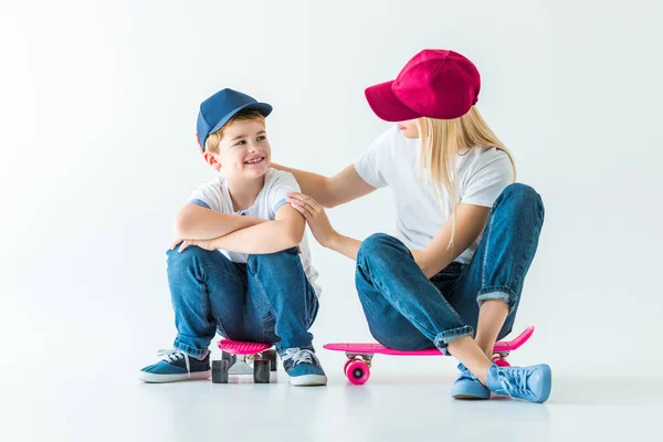 Mother sitting on skate and hugging smiling son on white — Stock Photo