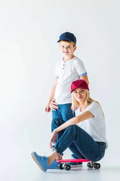 Mother sitting on skate, hugging son and looking at camera on white — Stock Photo