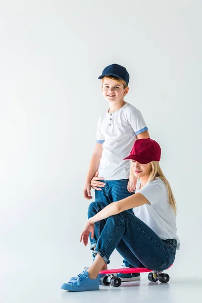 Madre sentada en el patín y abrazando hijo en blanco - foto de stock