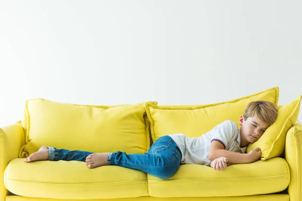 Entzückender Junge schläft auf gelbem Sofa isoliert auf weißem Grund — Stockfoto