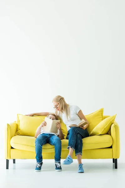 Mamãe e filho lendo livro no sofá amarelo no branco — Fotografia de Stock