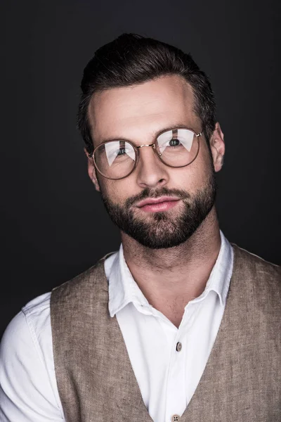 Retrato de homem bonito e confiante em óculos e colete elegante, isolado em cinza — Fotografia de Stock